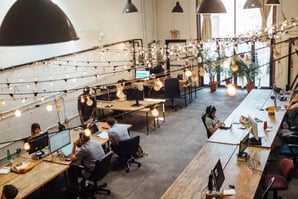 Modern open office workspace with employees at desks under string lights