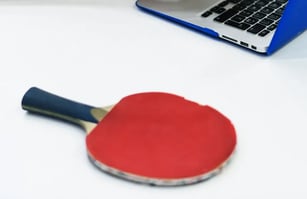 Ping pong paddle next to a laptop on a desk