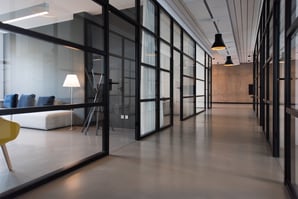 Modern office hallway with glass-walled conference rooms and contemporary furniture