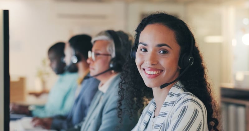 Smiling woman with headset in call center with coworkers in background