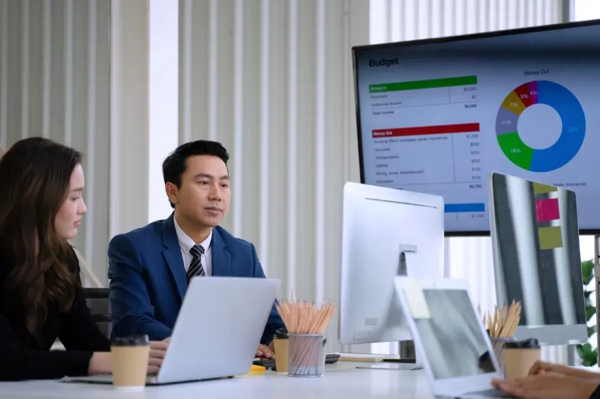 Business professionals reviewing budget charts and data on computer screens