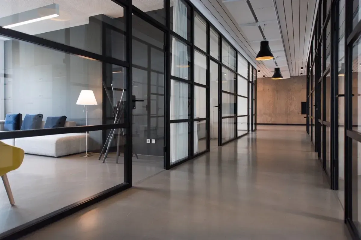 Modern office hallway with glass-walled conference rooms and contemporary furniture