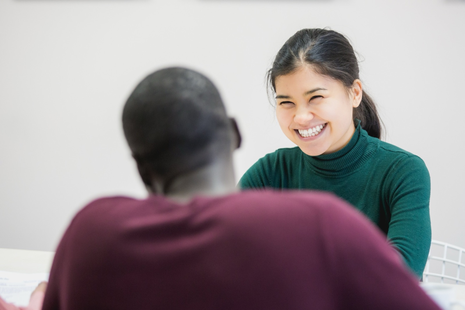 Woman smiling warmly during conversation with person in purple shirt