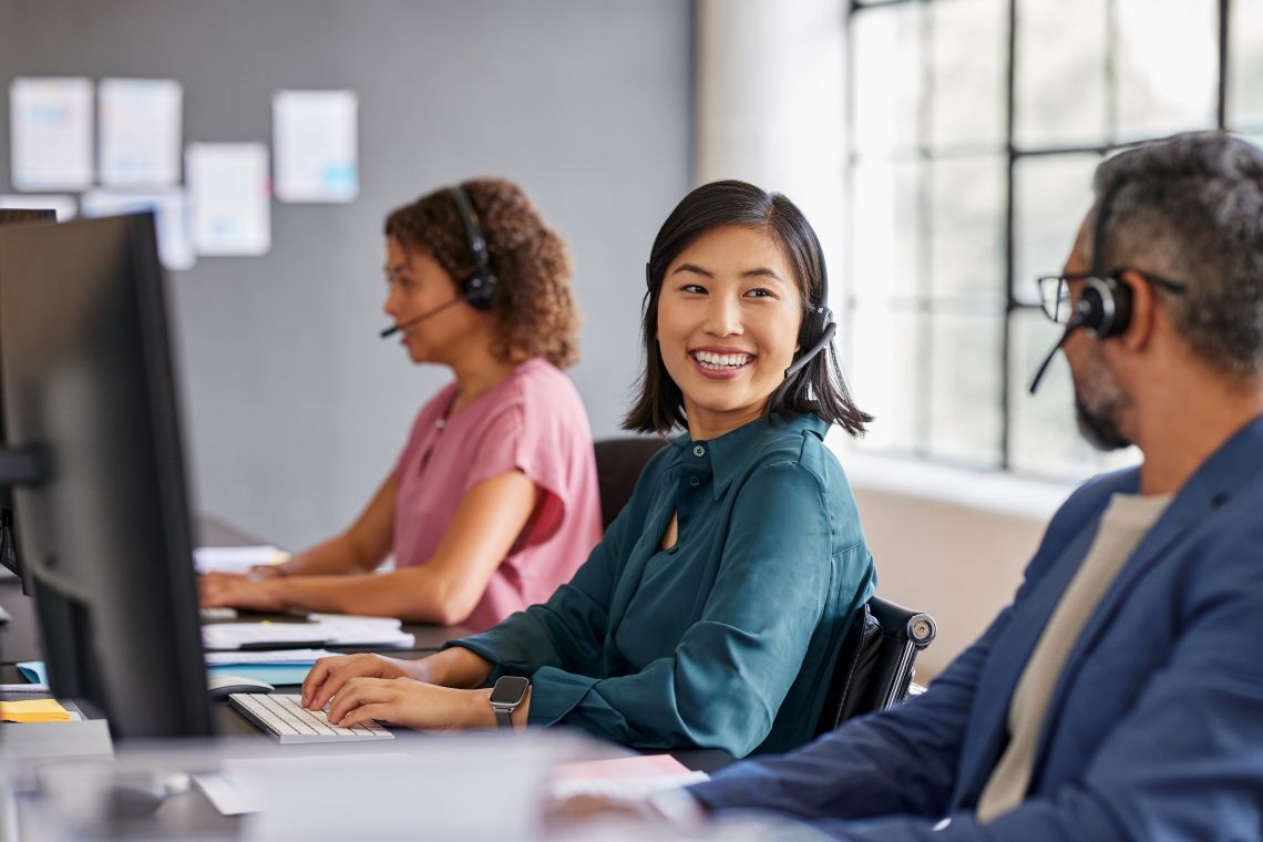 Three diverse customer service representatives wearing headsets at office workstations