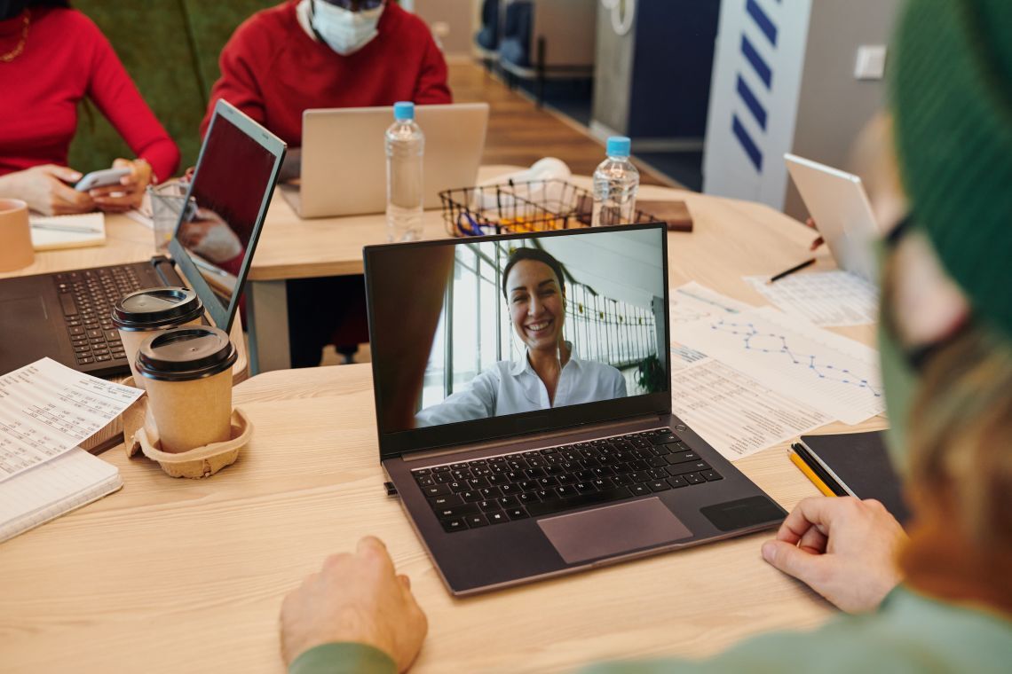 Business team in video conference call with smiling woman on laptop screen